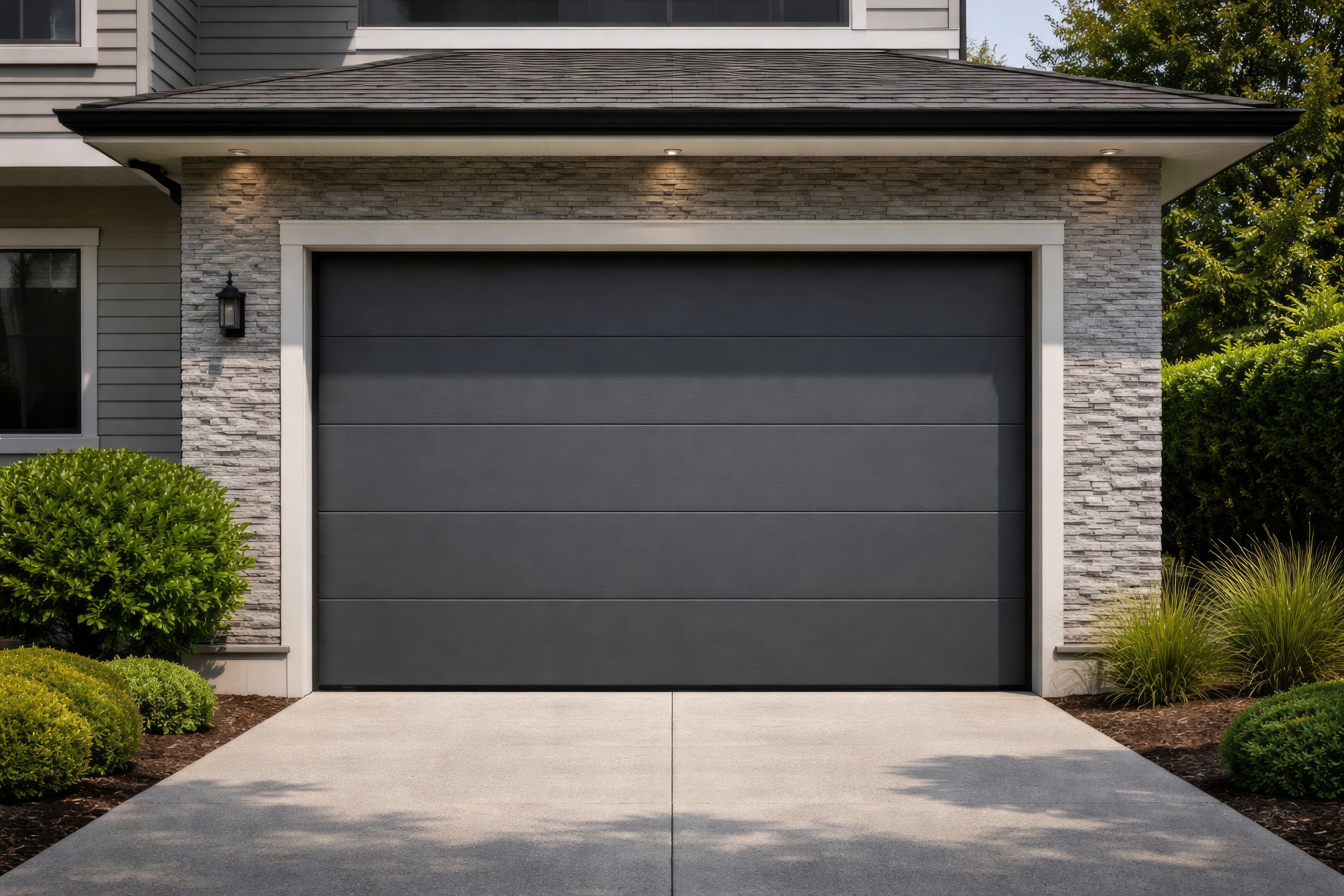 Modern attached garage with dark flush-panel door, stone veneer and gray siding