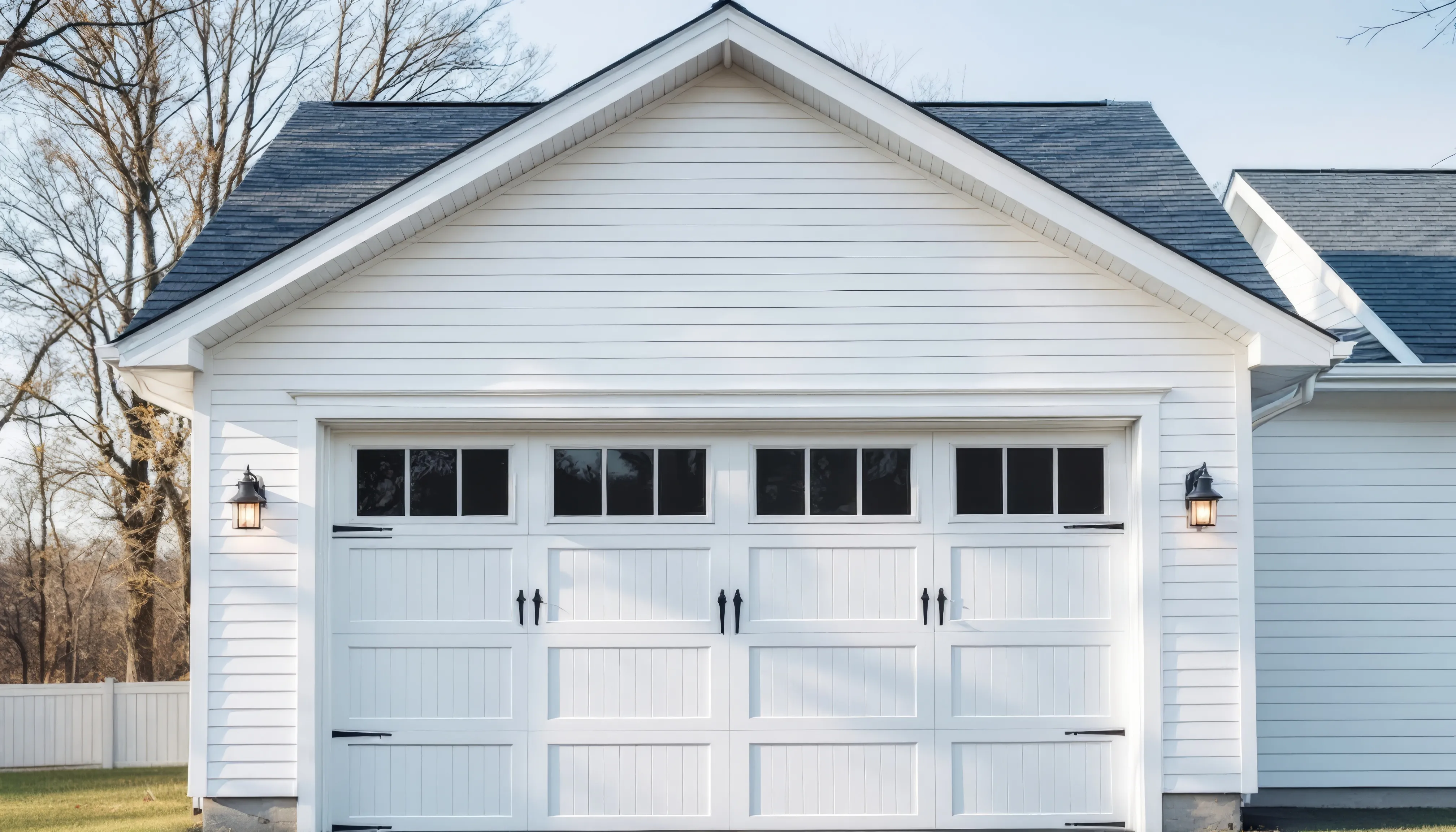 White attached garage with carriage-style door, black hardware and exterior lanterns