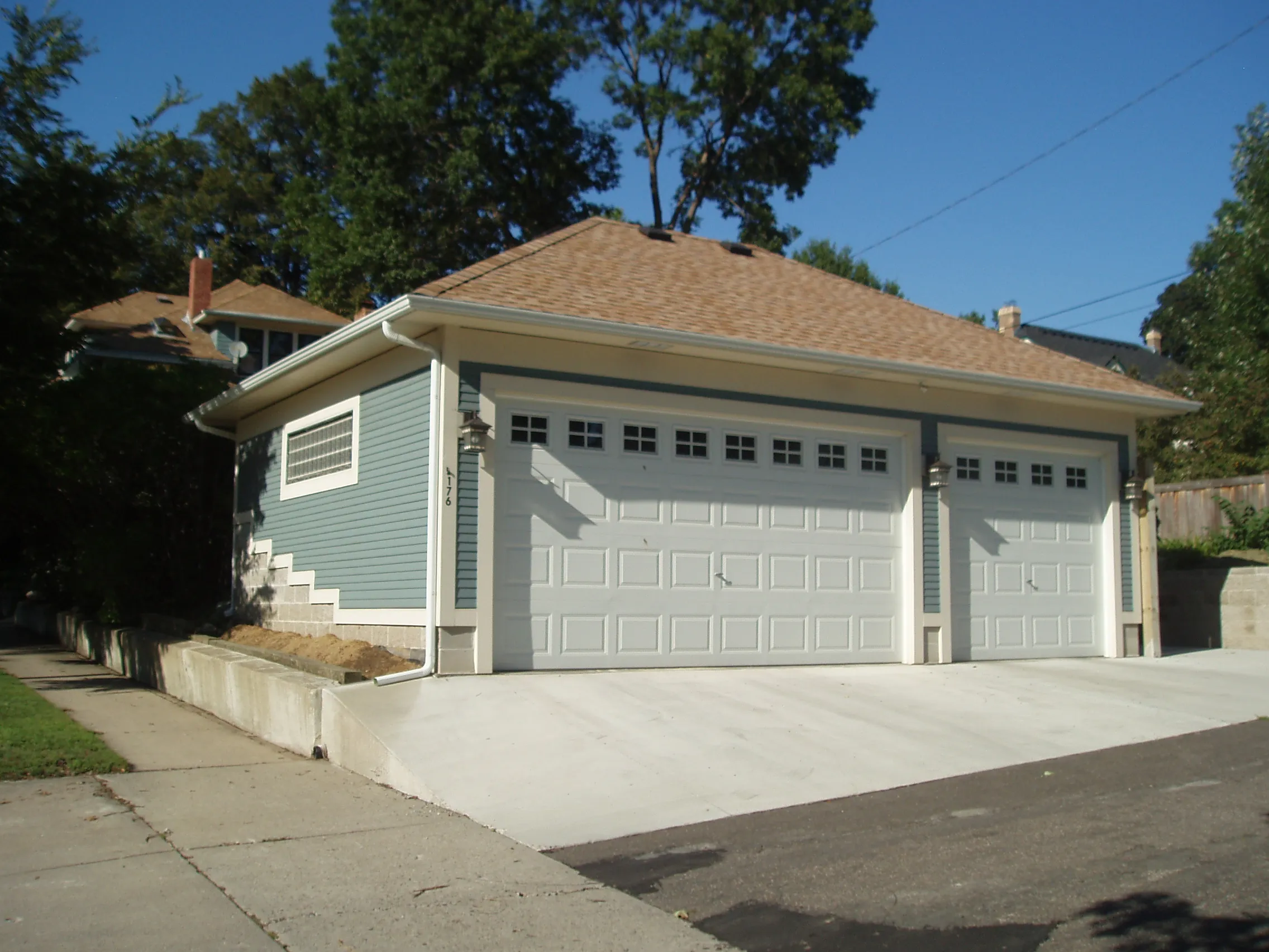 Custom three-car detached garage with blue siding, white doors and concrete driveway