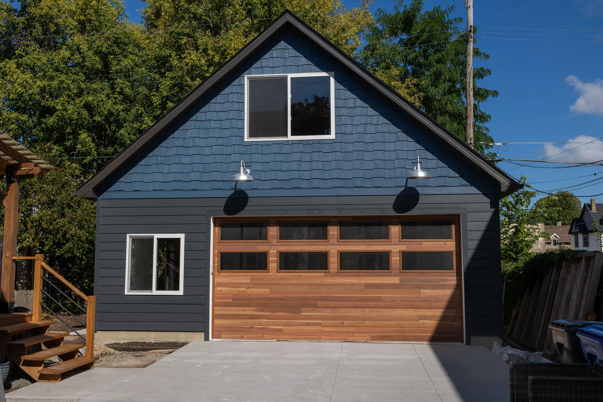 Custom detached garage with dark blue siding, cedar garage door and upper-level windows