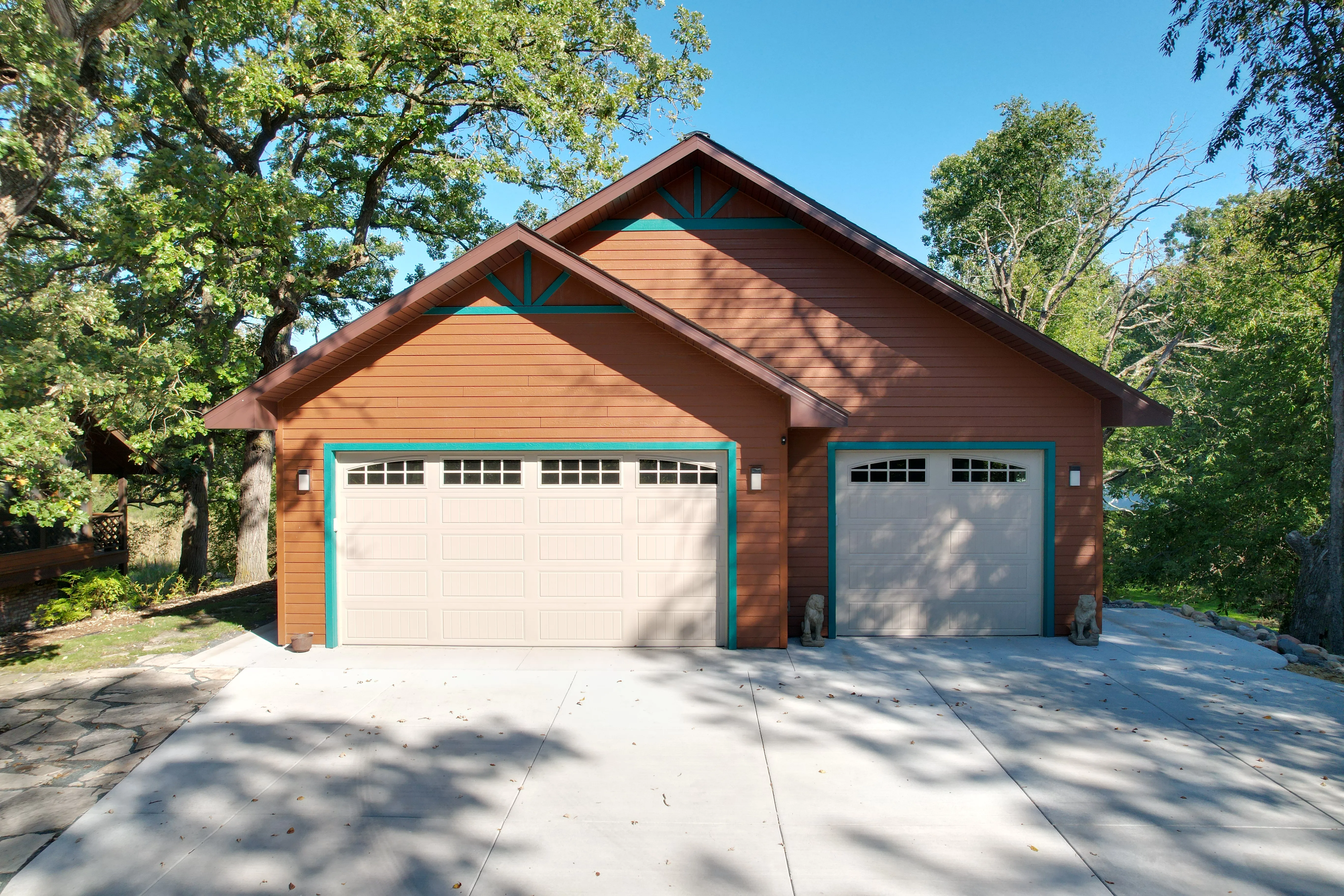 Custom three-car detached garage with brown siding, contrasting trim and carriage-style doors