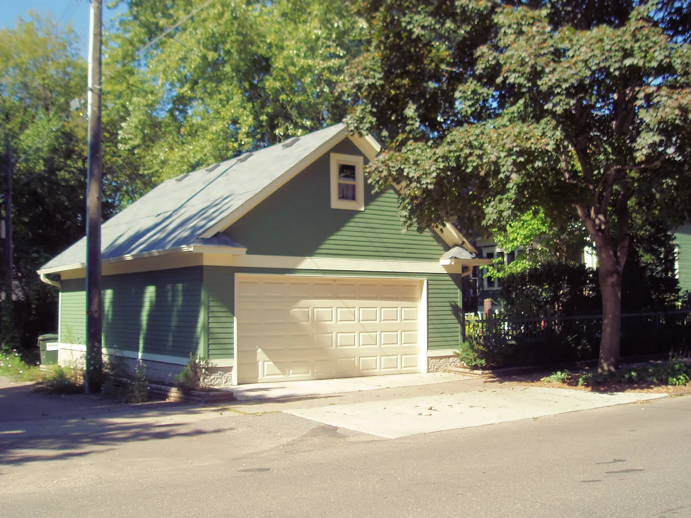 Green two-car detached garage with loft, steep gable roof and upper-level window