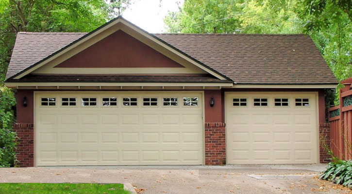 Red detached three-car garage with tan garage doors.