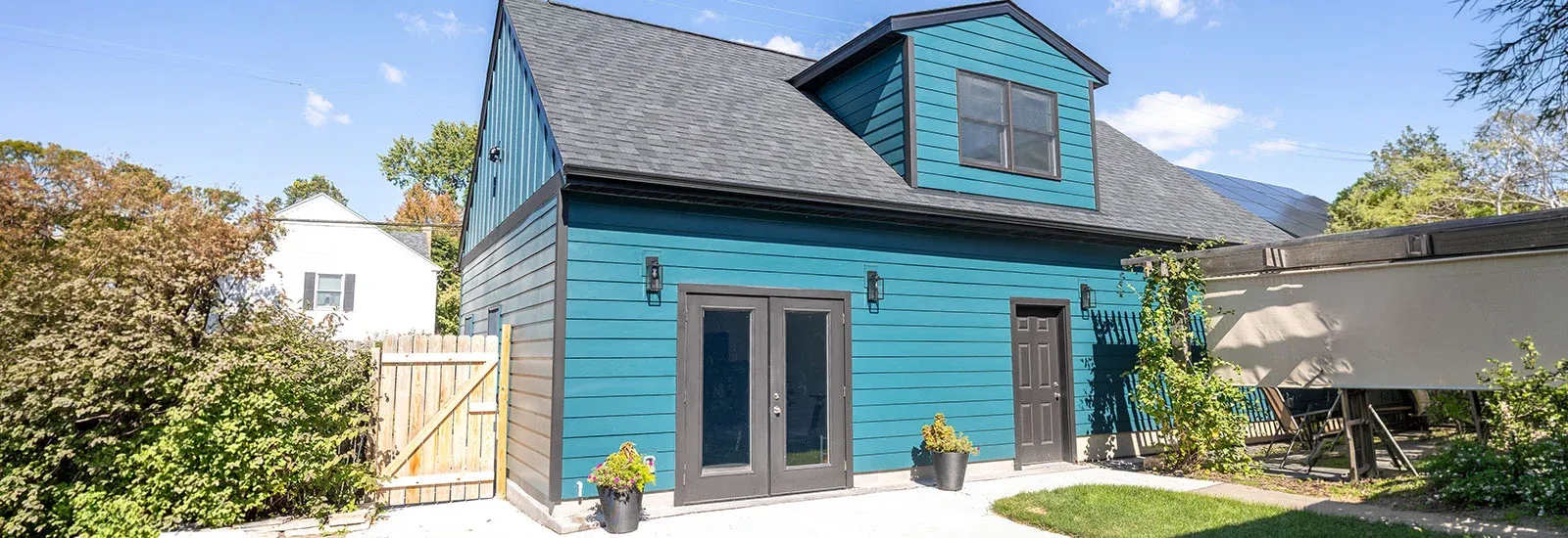 Custom detached garage with loft, teal siding, upper dormer and side entry doors