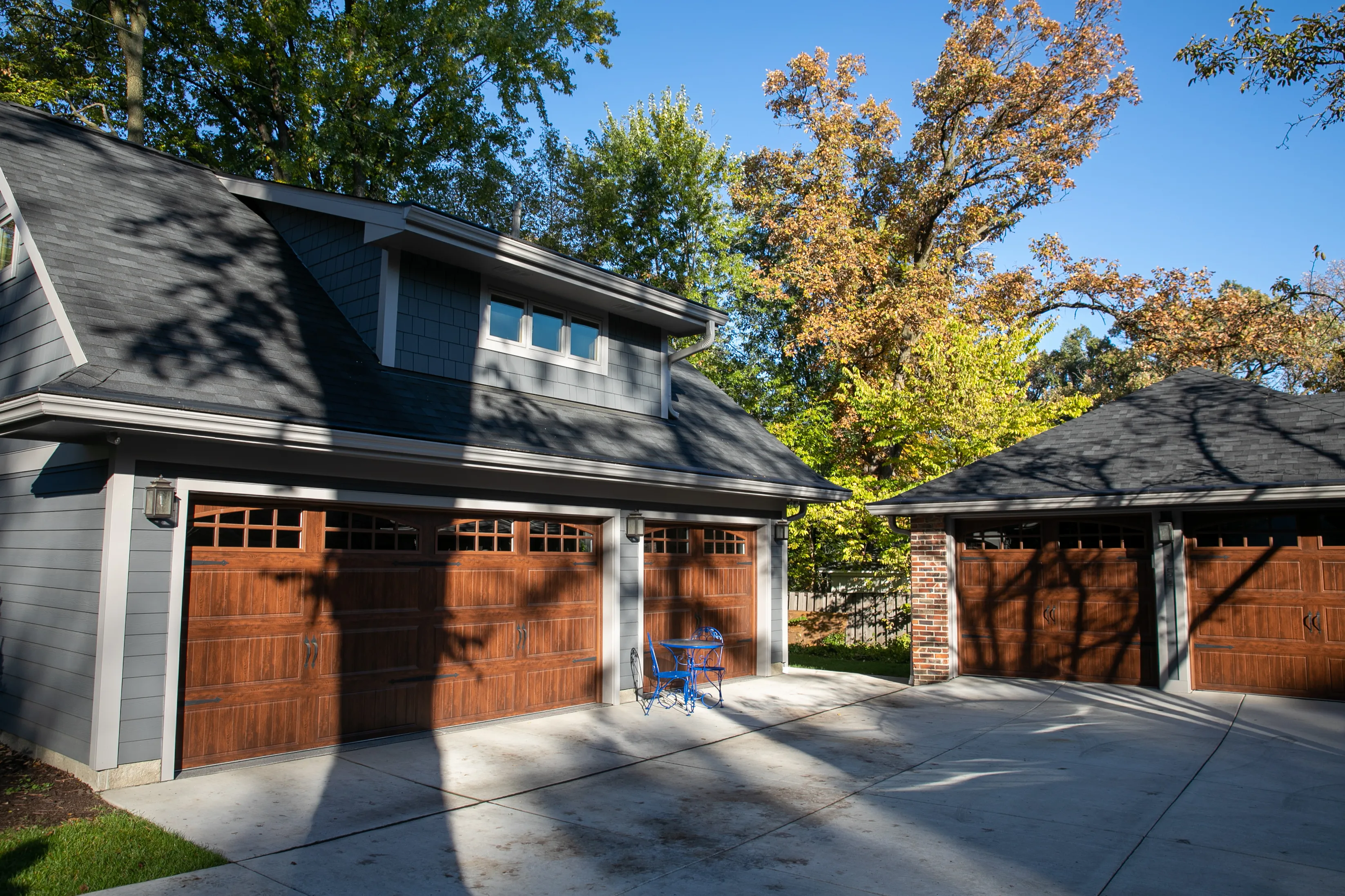 Custom multi-bay detached garage with loft, gray siding, dormer windows and wood garage door