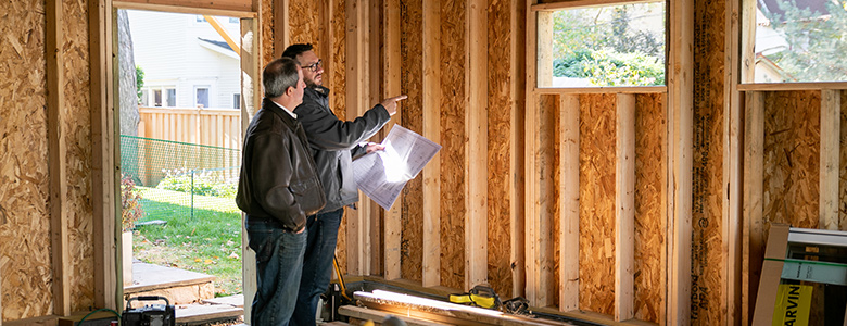 Guys talking over garage blueprints