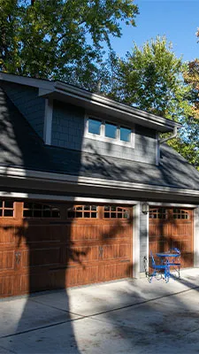 Custom attached two-car garage with wood doors and upper dormer windows