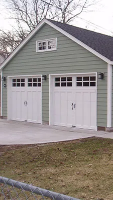 Detached two-car garage with green siding and white carriage-style doors