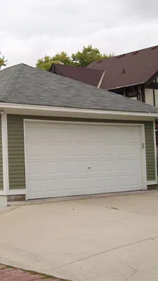 Detached two-car garage with a wide white door, hip roof and concrete driveway