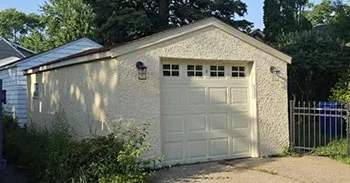 Single-car detached garage with white stucco exterior and paneled overhead door