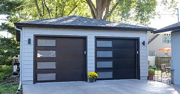 Modern two-car detached garage with gray siding and black glass-panel garage doors
