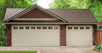 Custom three-car detached garage with brick accents, beige siding and separate overhead doors